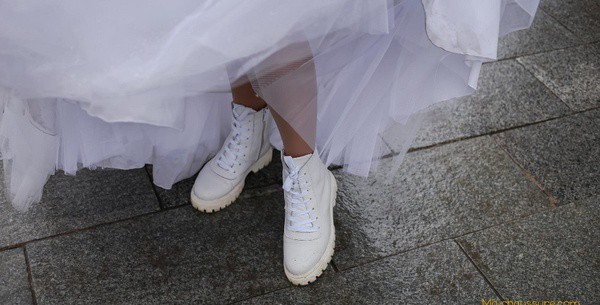 Femme qui porte une paire de baskets de mariage sur le trottoir