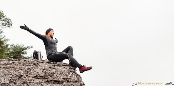 Femme qui porte des chaussures d'alpinisme assise en haut d'une montagne