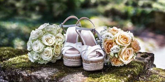 Paire de chaussure compensée mariage posée à côté de deux bouquets
