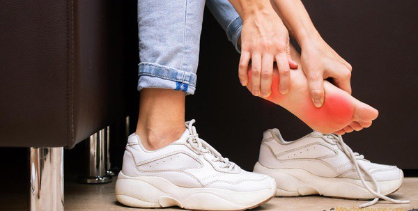 Femme avec pieds douloureux qui enfile des chaussures orthopédiques