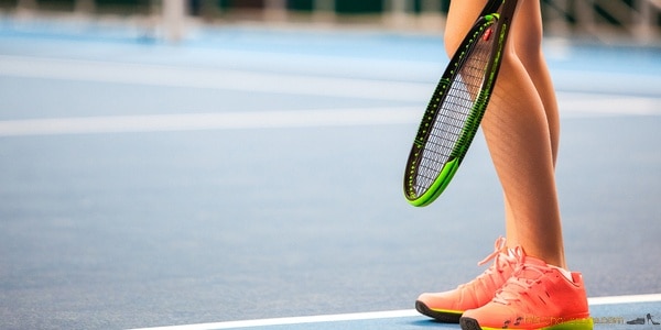 Femme sur une court de tennis qui chaussure des pointes athlétisme